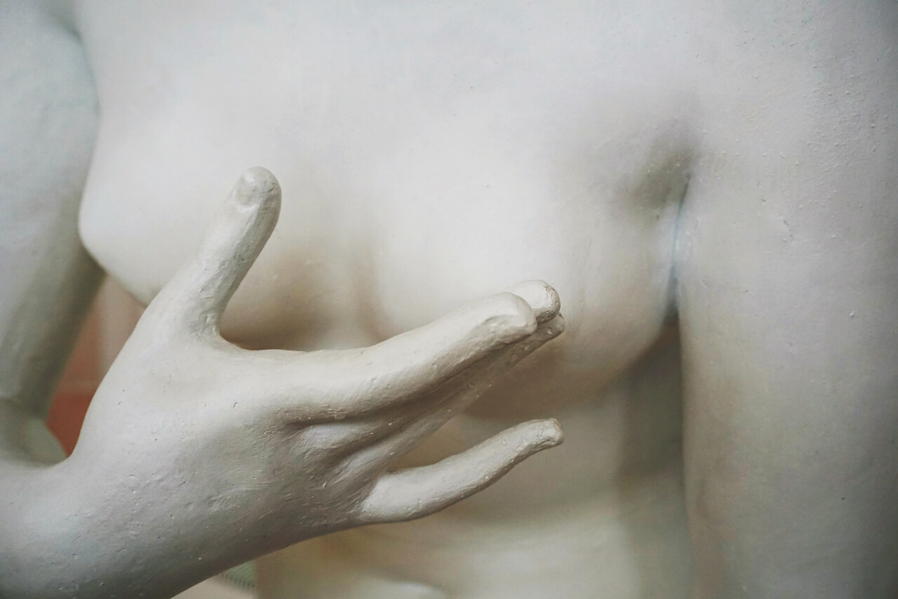 Skulptura na kojoj žena drži ruku ispred dojke