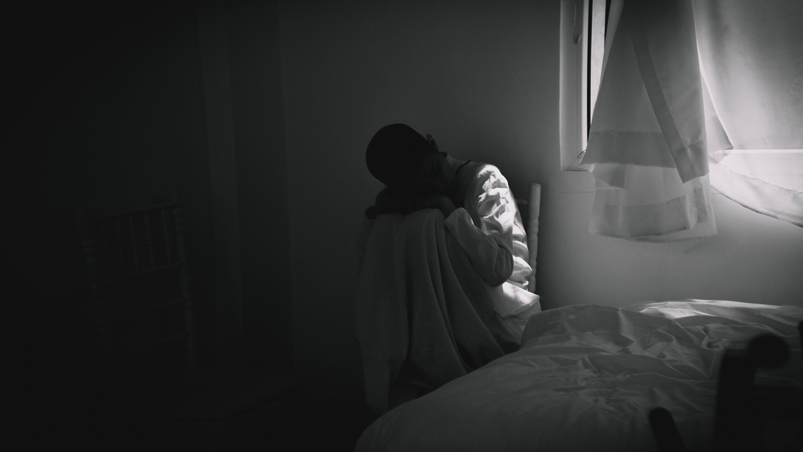 crno bijela fotografija djeteta u kutu bijele sobe