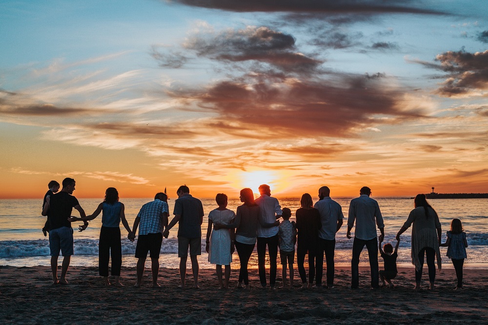 velika obitelj na plaži gleda zalazak sunca