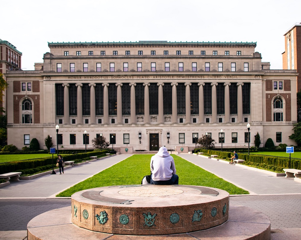 student sjedi ispred glavne zgrade sveučilišta columbia u new yorku