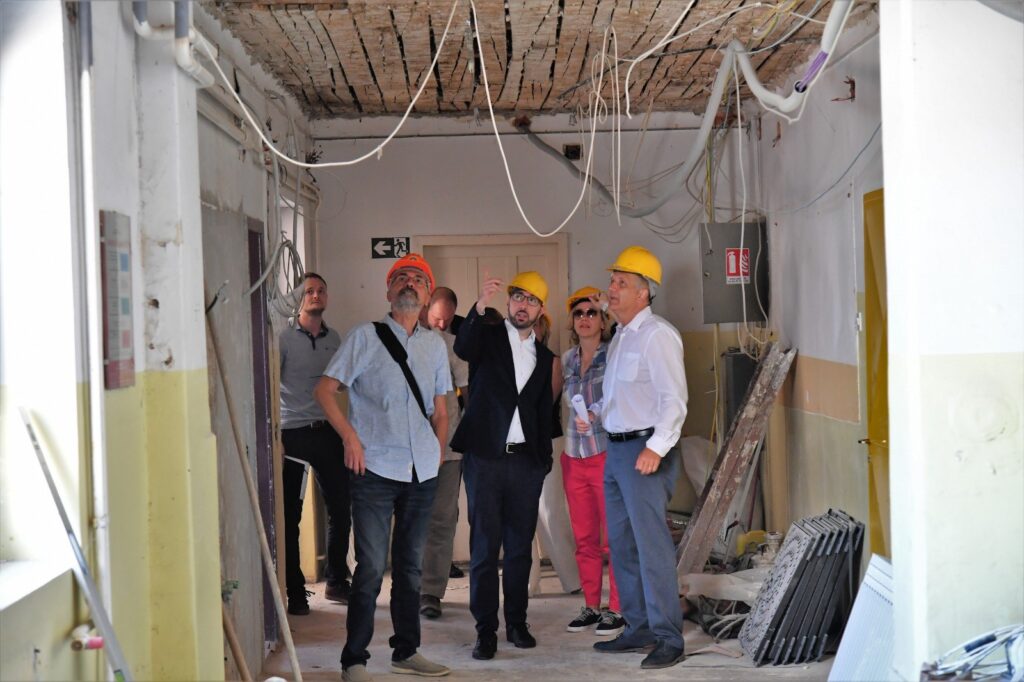 gradonačelnik zagreba tomislav tomašević sa zamjenicim ai radnicima unutar škole u kojoj su radovi, prstom pokazuje na žice koje vise sa stropa