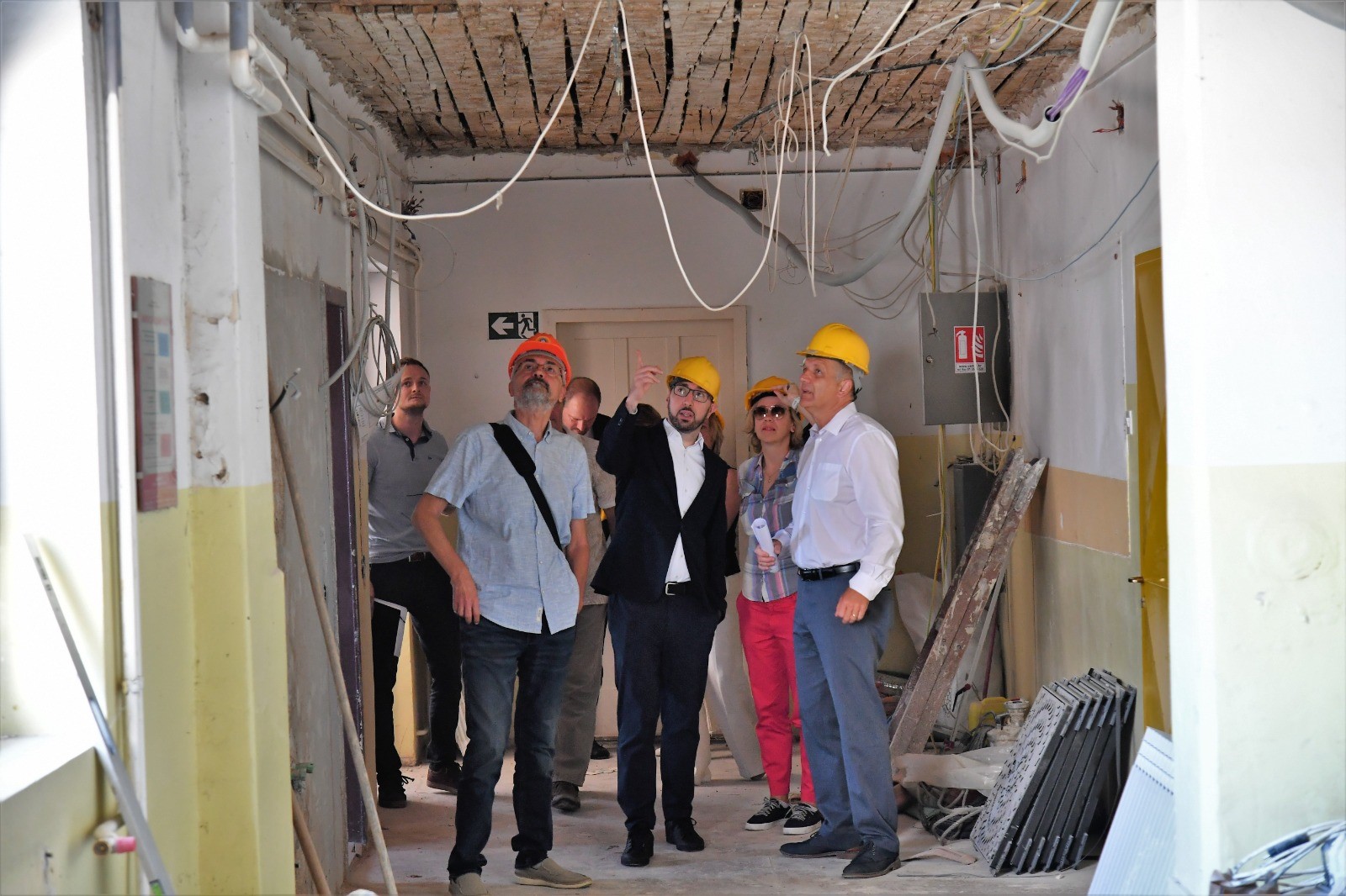 gradonačelnik zagreba tomislav tomašević sa zamjenicim ai radnicima unutar škole u kojoj su radovi, prstom pokazuje na žice koje vise sa stropa