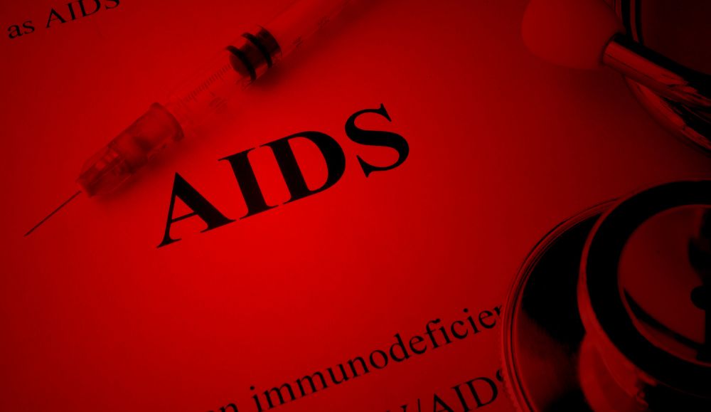 AIDS ispisan na papiru kraj igle i stetoskopa u crvenom