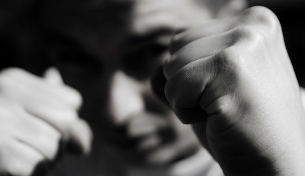 crno bijela fotografija mladića koji drže ruke ispred lica u šakama spreman za tučnjavu